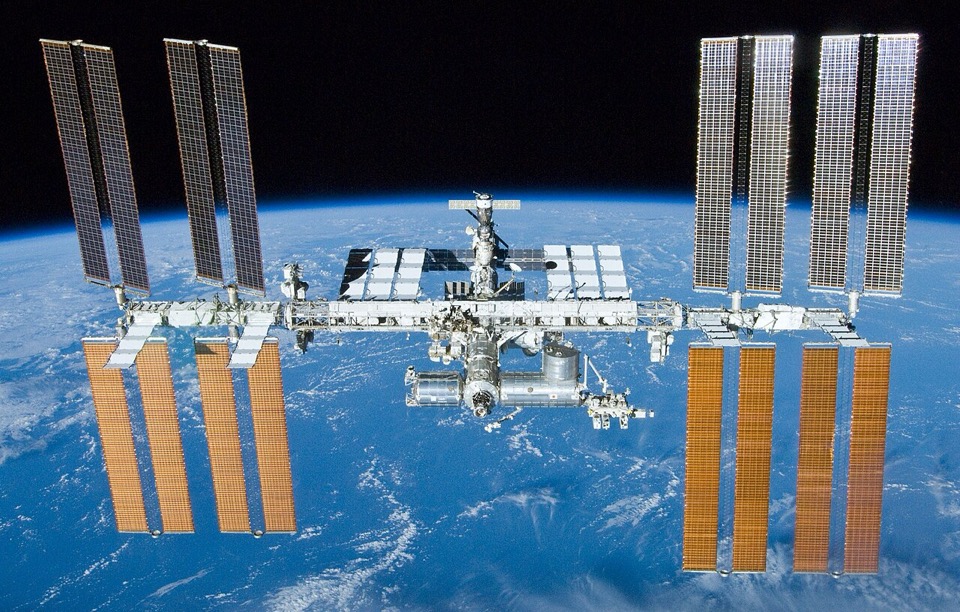 The International Space Station orbiting above Earth, its solar arrays and truss extended, photographed from the Space Shuttle Atlantis.
